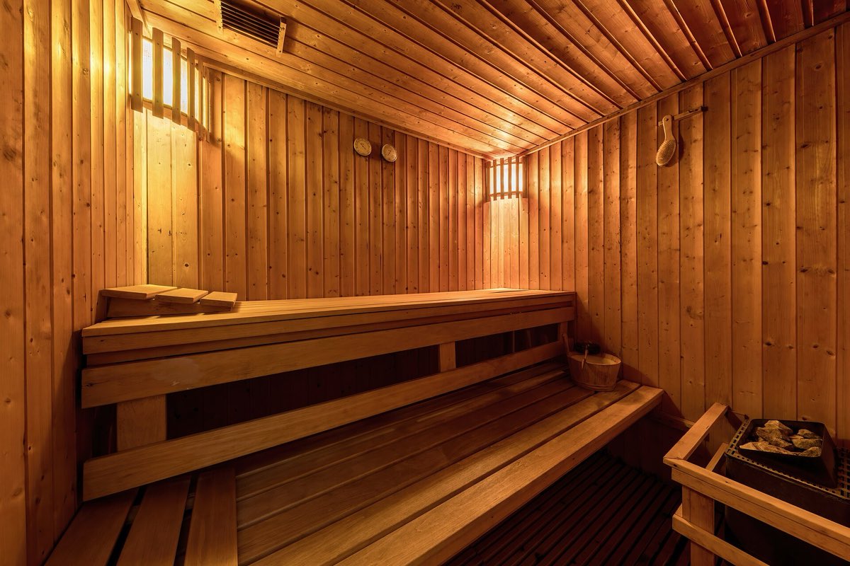 Innenansicht einer hölzernen Sauna mit Holzbänken und Saunaofen